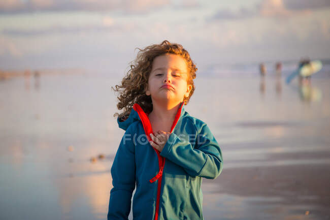 Niño rizado en rayas caminando en la playa en el fondo borroso de la naturaleza - foto de stock