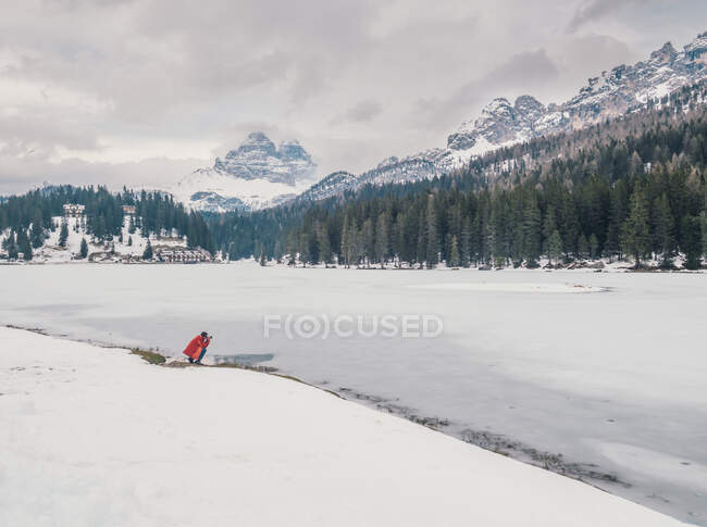 Personne méconnaissable debout dans la neige entourée de forêts et de montagnes — Photo de stock