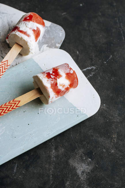 Watermelon and cream ice-cream on sticks on boards on dark background — Stock Photo
