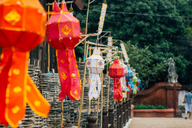 Colorful national lanterns with ornaments hanging in row on yard of temple, Thailand — Stock Photo