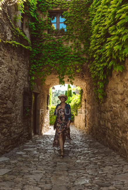 Женщина в платье и шляпе прогулка по улице средневекового города — стоковое фото