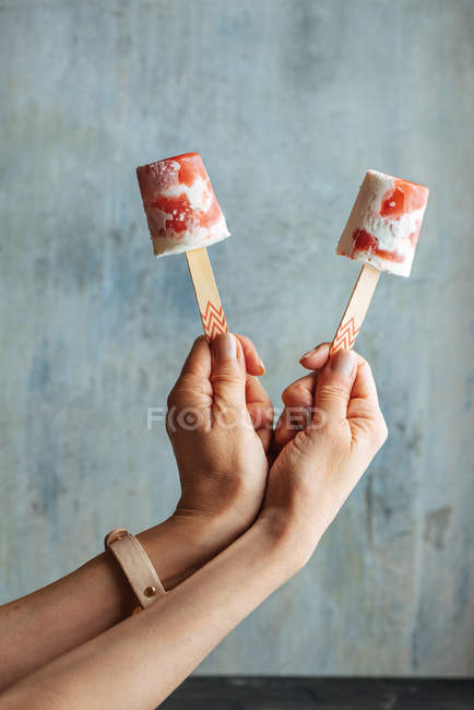 Mãos femininas segurando melancia e sorvete creme contra fundo azul claro — Fotografia de Stock