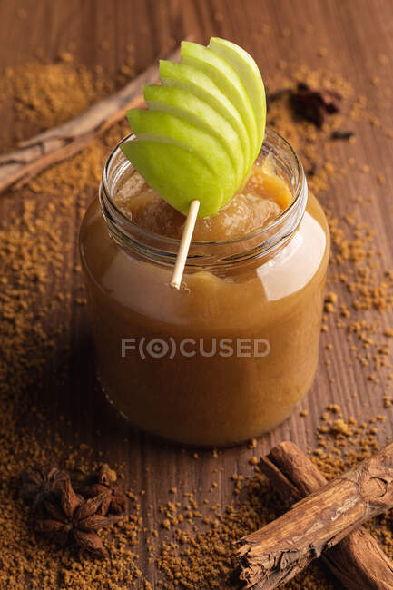Decorado com maçã verde apetitoso suculento molho de maçã em frasco de vidro e canela no fundo de madeira — Fotografia de Stock
