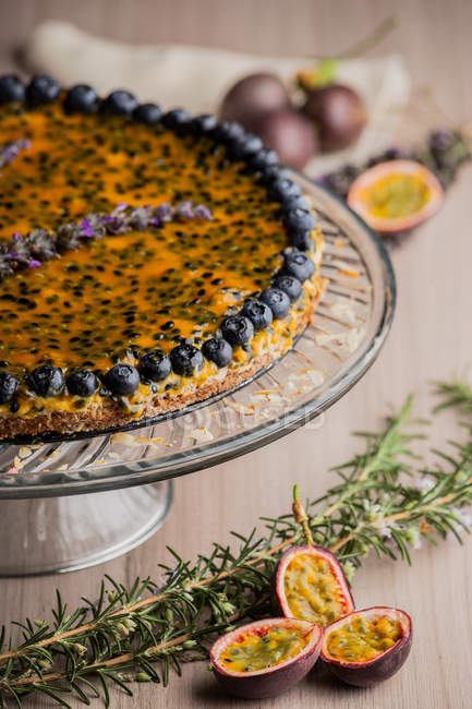 Appetizing fragrant passion fruit pie with blueberry topping decorated with bunch of lavender on cake stand — Stock Photo