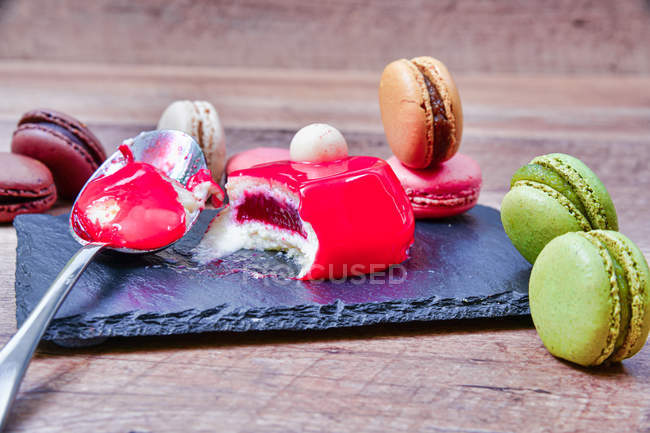 Served mousse dessert with colorful macaroons on slate board — Stock Photo