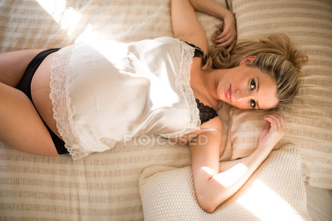 Retrato de mulher grávida em roupa interior relaxante em cama confortável em casa — Fotografia de Stock