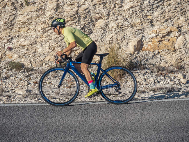 Primer plano del hombre sano montar en bicicleta en carretera de montaña en el día soleado - foto de stock