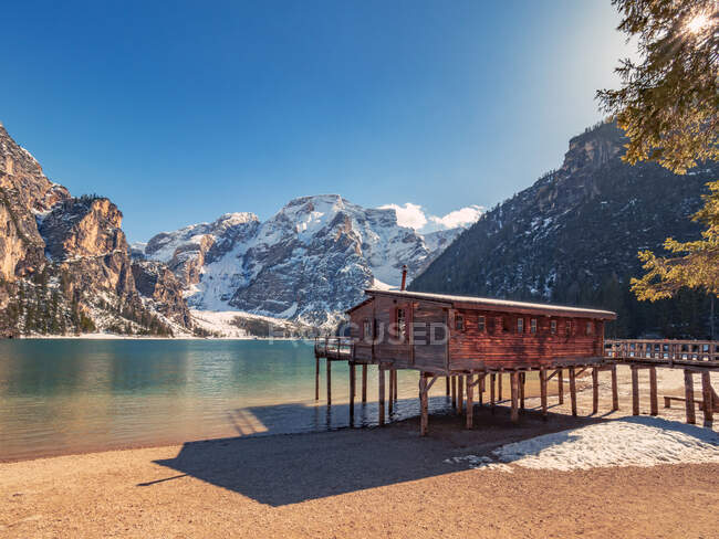 Bela paisagem com casa de madeira stilt no lago de tirar o fôlego cercado por montanhas nevadas rochosas — Fotografia de Stock