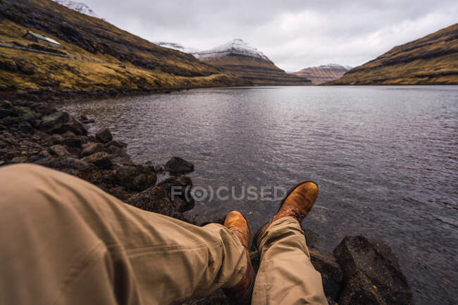 Unbekannter sitzt am See und zeigt Beine beim Entspannen auf Färöer-Insel — Stockfoto