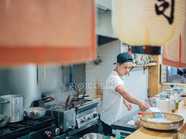 From above view of kitchen with young man cooking Japanese dish ramen in oriental restaurant — Stock Photo
