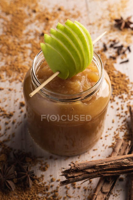 Décoré avec pomme verte appétissante compote de pommes juteuse dans un bocal en verre et cannelle sur fond en bois — Photo de stock