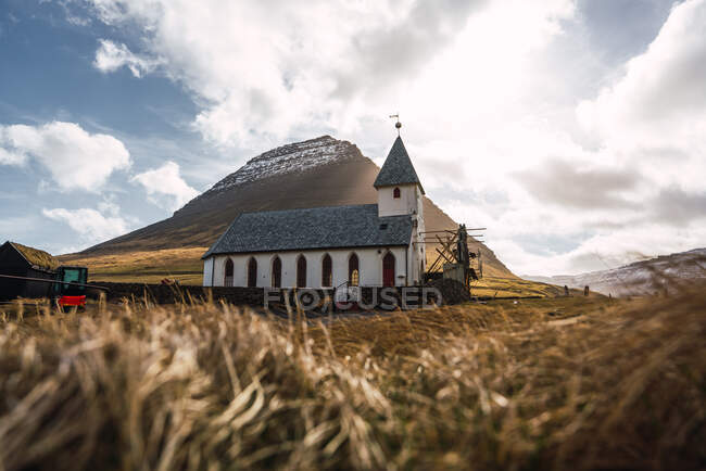 Kleine Kirche in trockenem Tal in der Nähe eines hohen Hügels auf der Insel Färöer — Stockfoto