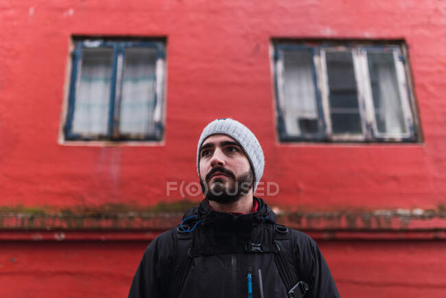 Homme barbu regardant loin tout en se tenant devant le bâtiment rouge dans l'île faroe — Photo de stock