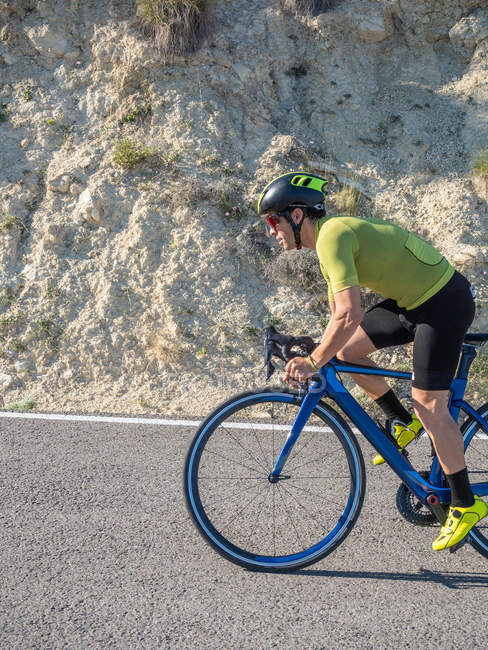 Крупный план здорового человека, катающегося на велосипеде по горной дороге в солнечный день — стоковое фото