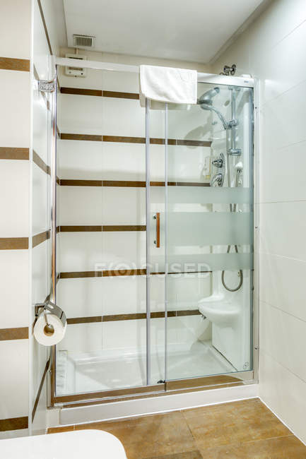 Интерьер ванной комнаты в минималистском современном стиле украшен белой плиткой с душевой кабиной — стоковое фото