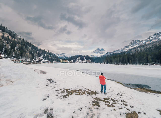 Unrecognizable person standing in snow surrounded by forest and mountains — Stock Photo