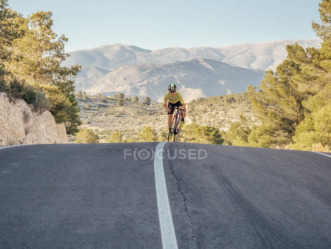 Здоровый человек езда на велосипеде по горной дороге в солнечный день — стоковое фото