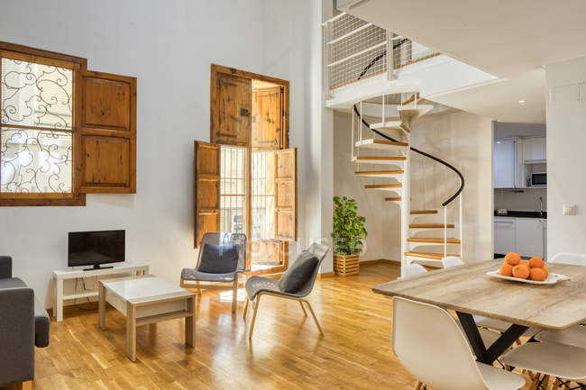 Interior de comedor sencillo y elegante y escaleras en moderno piso dúplex a la luz del día - foto de stock