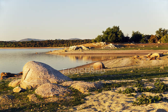 Vista pintoresca del lago con ruta rural, bosque de abetos y colinas en el Lago Valmayor España. - foto de stock