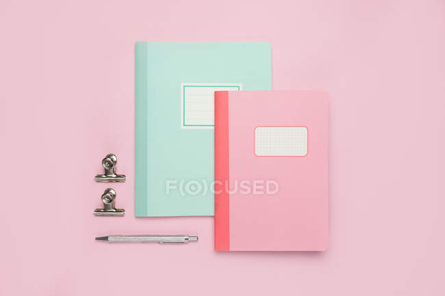 Composición de cuadernos de colores, pluma y arreglado en escritorio rosa - foto de stock