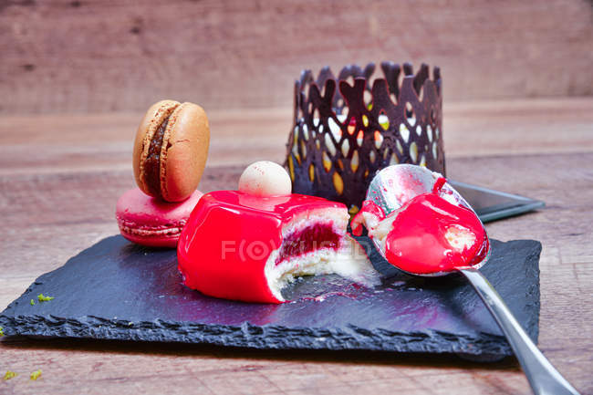 Served mousse dessert with colorful macaroons on slate board — Stock Photo
