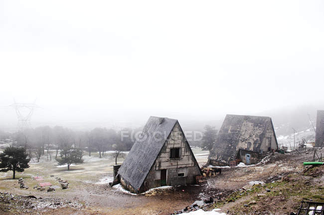 Vecchi cottage climatizzati nella campagna innevata il giorno nebbioso — Foto stock