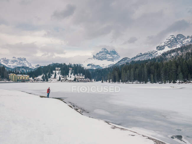Pessoa irreconhecível em pé na neve cercada por florestas e montanhas — Fotografia de Stock
