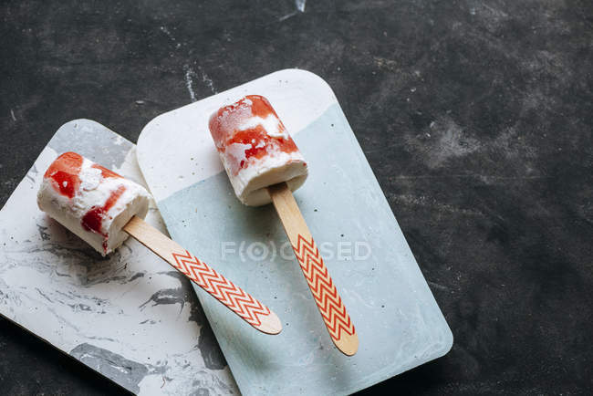 Two watermelon and cream popsicles on boards on dark background — Stock Photo