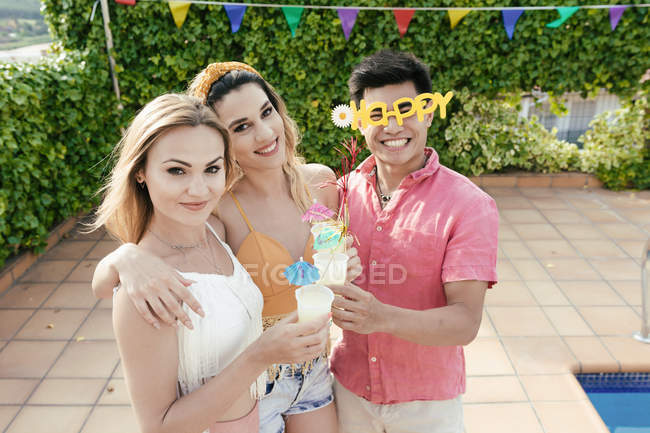 Group of friends having a pool party while they dance, laugh and drink cocktails — Stock Photo