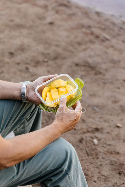 Detalle del hombre irreconocible comiendo fruta de mango en el bosque - foto de stock