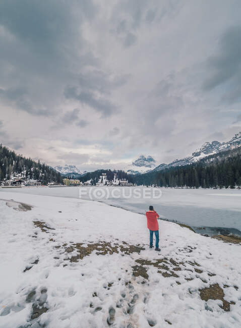 Pessoa irreconhecível em pé na neve cercada por florestas e montanhas — Fotografia de Stock