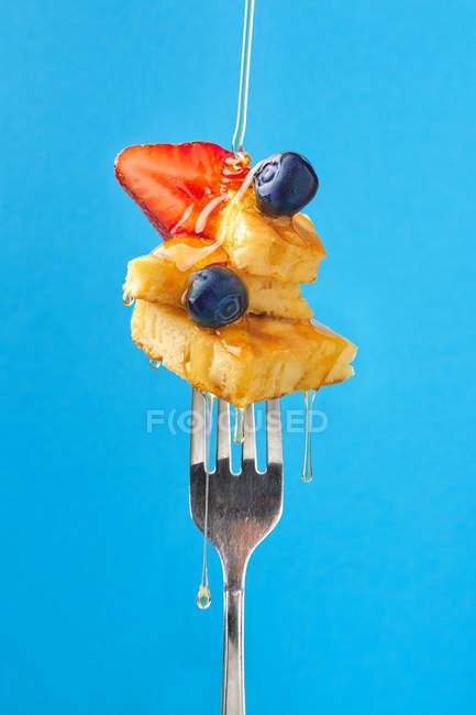 Composizione dolce dolce dolce con fragola e mirtilli aromatizzati dal miele su fondo blu — Foto stock