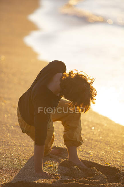 Vue arrière de l'homme sportif en pantalon jaune pieds nus effectuant une séance de méditation de yoga sur la plage de sable au coucher du soleil soir — Photo de stock