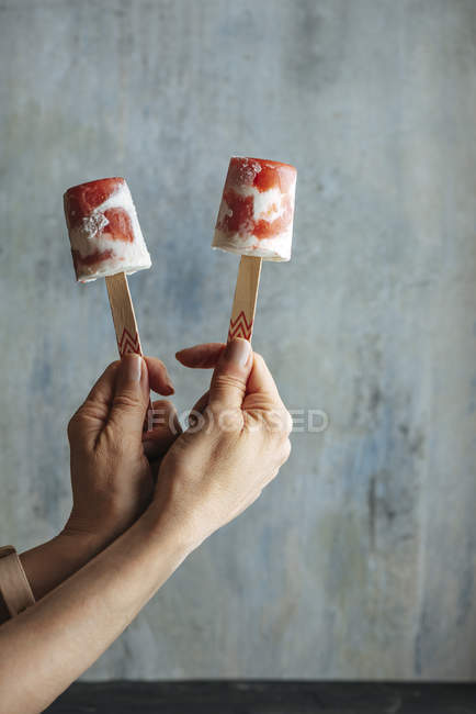 Mains féminines tenant pastèque et crème glacée sur fond bleu clair — Photo de stock