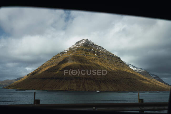 Increíble vista del lago con acantilado verde nevado en la isla de Faroe - foto de stock