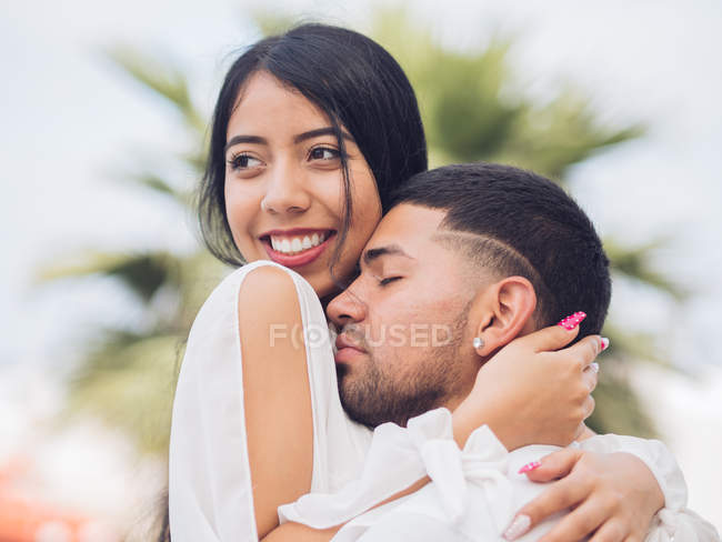 Junger schöner Mann mit geschlossenen Augen umarmt attraktive lächelnde Frau — Stockfoto