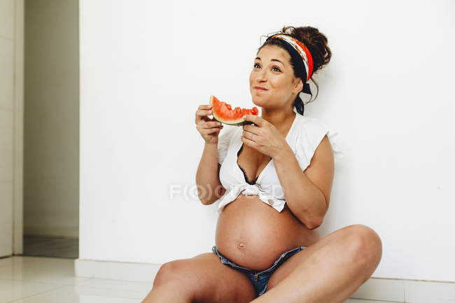 Mulher grávida alegre comer deliciosa melancia em casa — Fotografia de Stock
