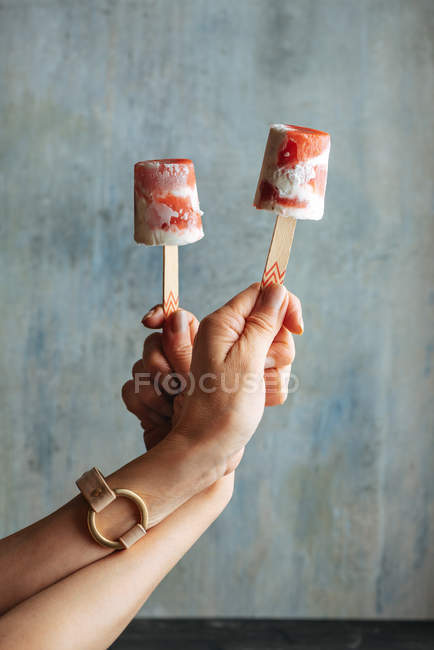 Mani femminili che tengono anguria e gelato alla panna sullo sfondo azzurro — Foto stock