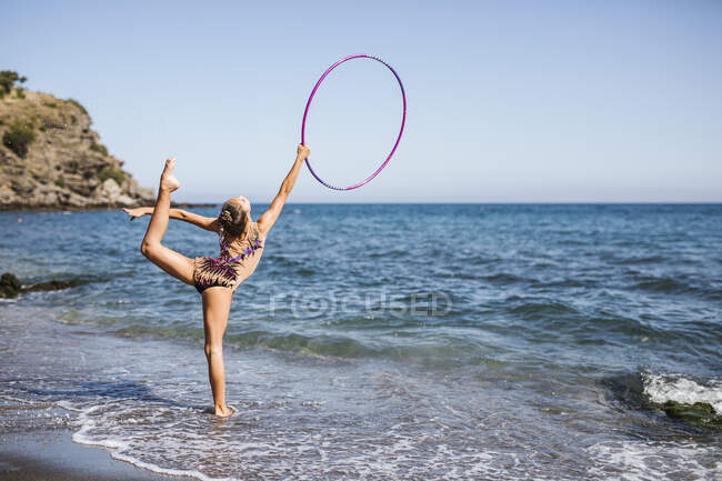Anmutiger Akrobat tritt mit Reifen am Strand auf — Stockfoto