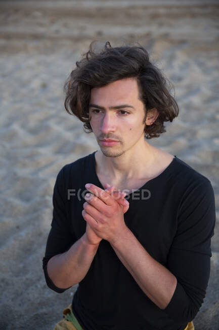 Jeune homme effectuant une méditation de yoga sur la plage de sable au coucher du soleil soir — Photo de stock