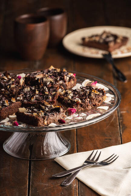 Сверху аппетитный ароматный коричневый торт с овсяными хлопьями в стеклянной пластине на деревянном фоне — стоковое фото