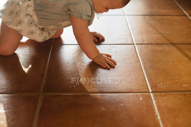 Ребенок с соском во рту ползает на четвереньках по полу — стоковое фото