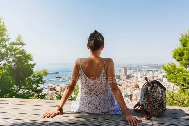 Donna sulla panchina guardando la vista della città dall'alto — Foto stock