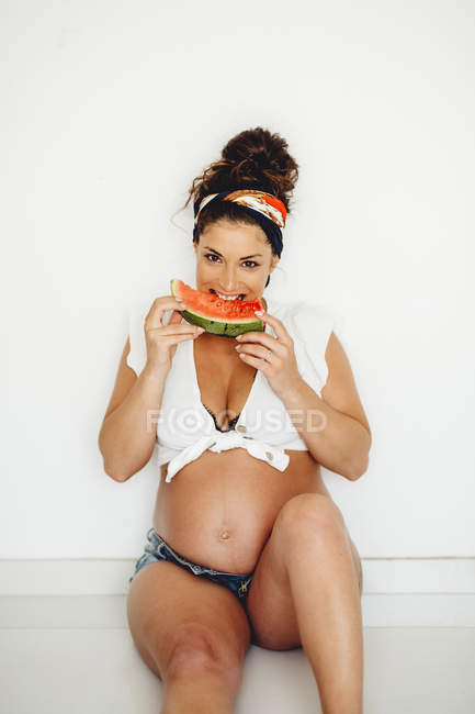 Gaie femme enceinte manger délicieuse pastèque à la maison — Photo de stock