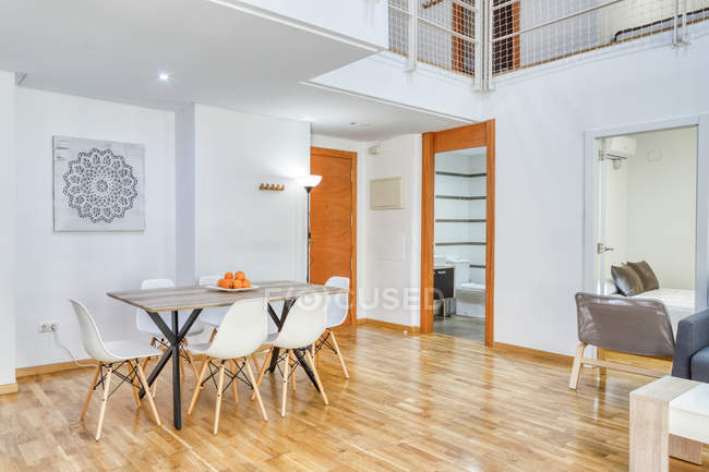 Интерьер просторной стильной столовой и лестницы в современной двухуровневой квартире при дневном свете — стоковое фото