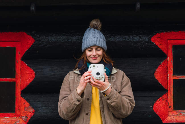 Mulher vestindo roupas de inverno na frente de uma cabine de madeira tirar foto — Fotografia de Stock