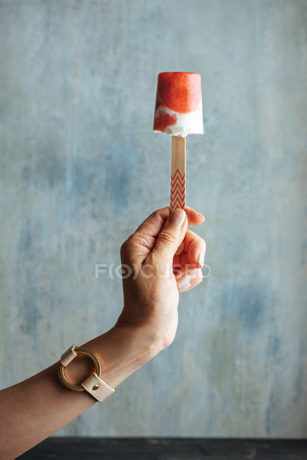 Mão feminina segurando melancia e sorvete creme contra fundo azul claro — Fotografia de Stock