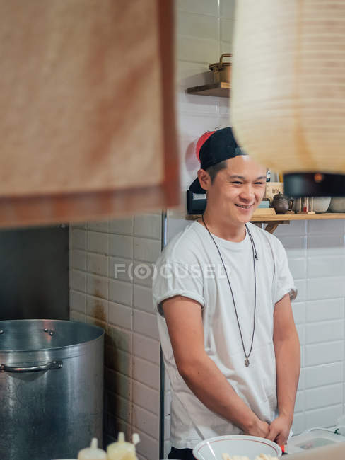 Junger Mann steht mit den Händen in den Taschen beim Kochen japanischer Ramen im Restaurant — Stockfoto