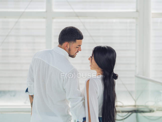 Vista posterior de la encantadora pareja joven en ropa ligera vinculación y besos con amor y ternura en el interior - foto de stock