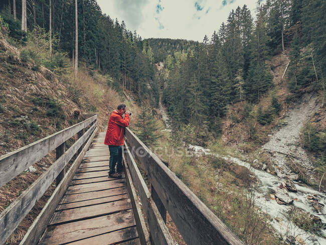 Vista laterale del viaggiatore che fotografa mentre cammina sul sentiero escursionistico della pittoresca zona delle Dolomiti — Foto stock